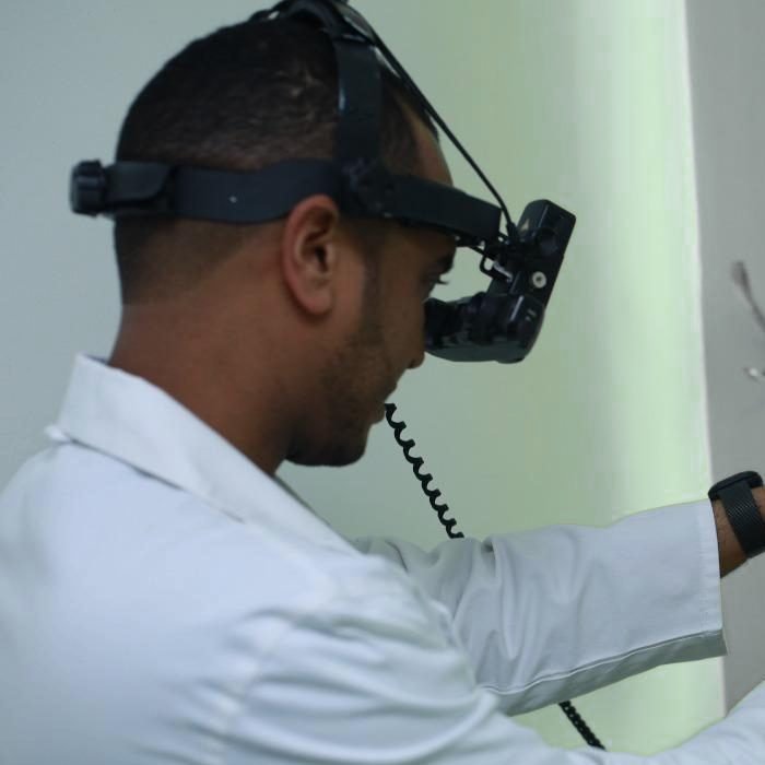 El Dr. De la Rosa con lupa binocular frontal durante una exploración.